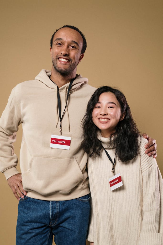 Cheerful volunteers in a studio portrait with volunteer badges, promoting community involvement.